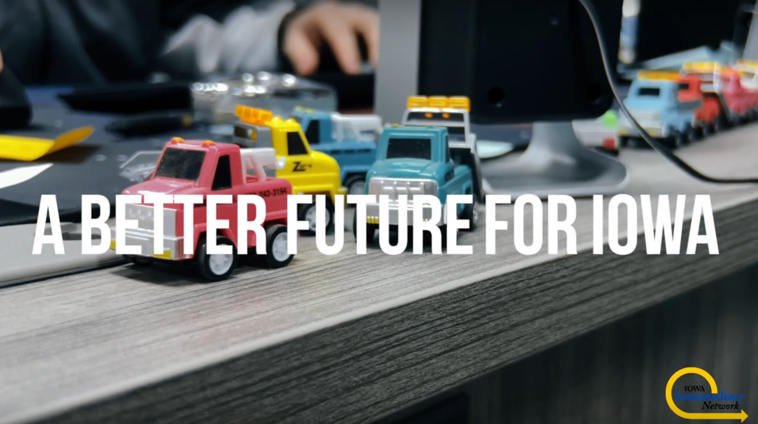 A photo of toy trucks on a desk with text over that reads: A better future for Iowa